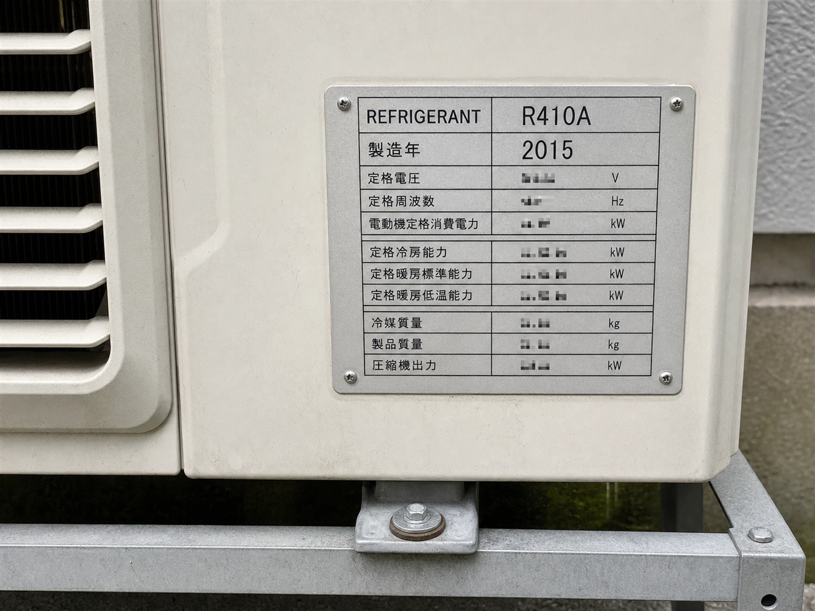 業務用エアコンの室外機に貼られた銘板。1行目にREFRIGERANT R410A、2行目に製造年2015と書かれている